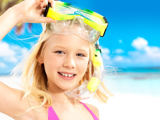 Retrato de la niña feliz disfrutando en la playa. Niña en edad escolar con máscara de natación en la cabeza.