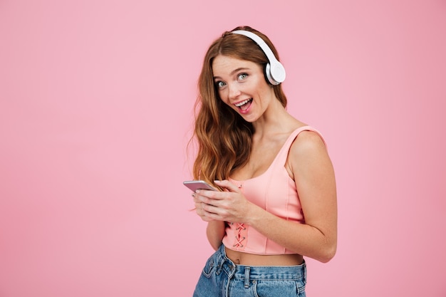 Retrato de una niña feliz emocionada en ropa de verano escuchando música