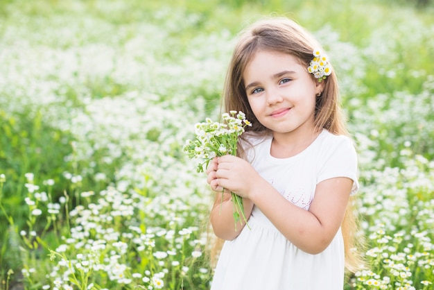 Retrato de niña feliz con flores blancas en la mano