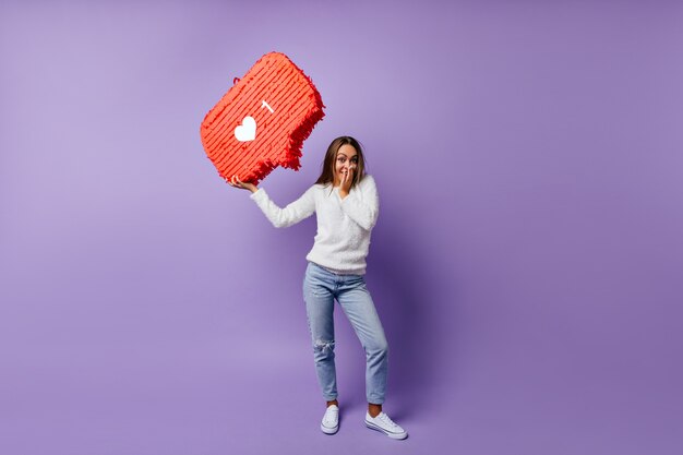 Retrato de niña feliz en jeans pensando en internet. Retrato de cuerpo entero de una mujer morena disfrutando de las redes sociales.