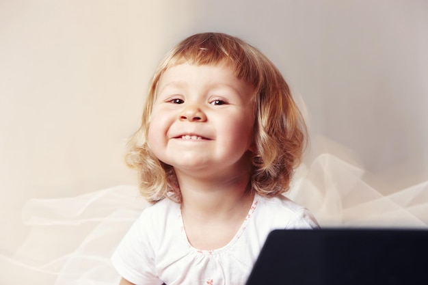 Retrato de una niña feliz y linda con un vestido blanco sobre un fondo blanco.