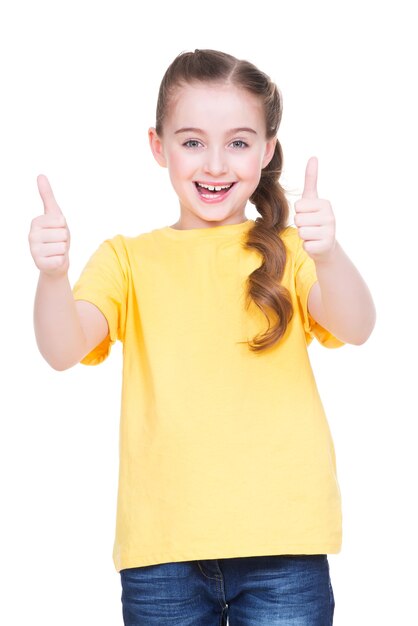 Retrato de niña feliz mostrando los pulgares para arriba gesto en camiseta amarilla, aislado sobre fondo blanco.