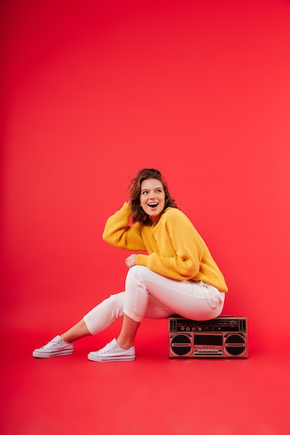 Retrato de una niña feliz sentada en un boombox