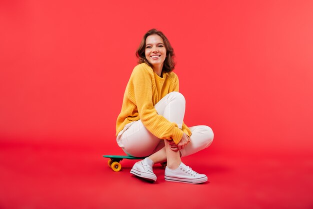 Retrato de una niña feliz sentada en una patineta