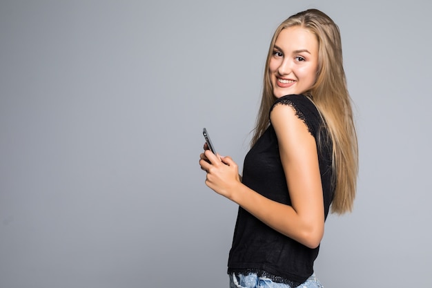 Retrato de una niña feliz con smartphone aislado sobre un fondo gris