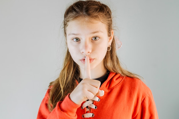 Retrato de una niña haciendo gesto de silencio