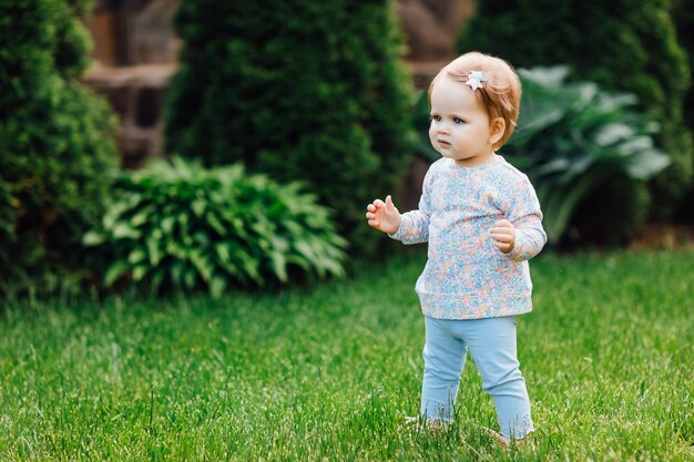 Retrato de niña hermosa, en el hermoso parque verde, sonríe suavemente