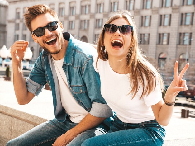 Retrato de niña hermosa sonriente y su novio guapo. Mujer en ropa casual jeans de verano. Muestra un signo de paz.