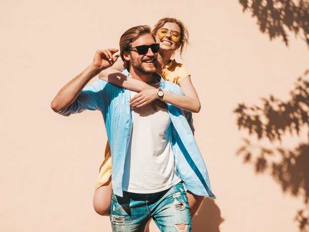 Retrato de niña hermosa sonriente y su novio guapo. Mujer en vestido casual de verano y hombre en jeans. Feliz familia alegre. Mujer divirtiéndose en la calle cerca de la pared