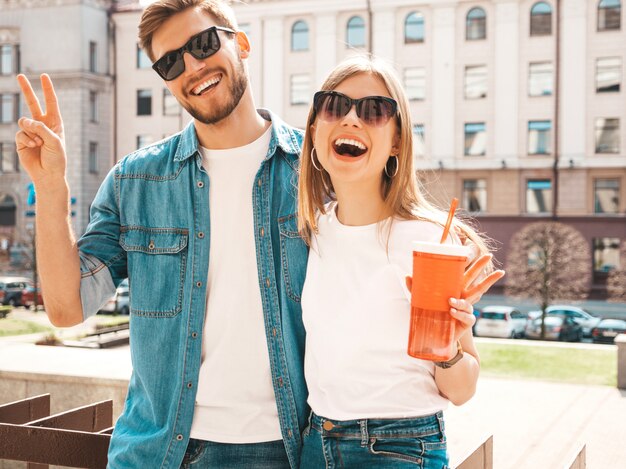 Retrato de niña hermosa sonriente y su novio guapo en ropa casual de verano. . Con botella de agua y paja