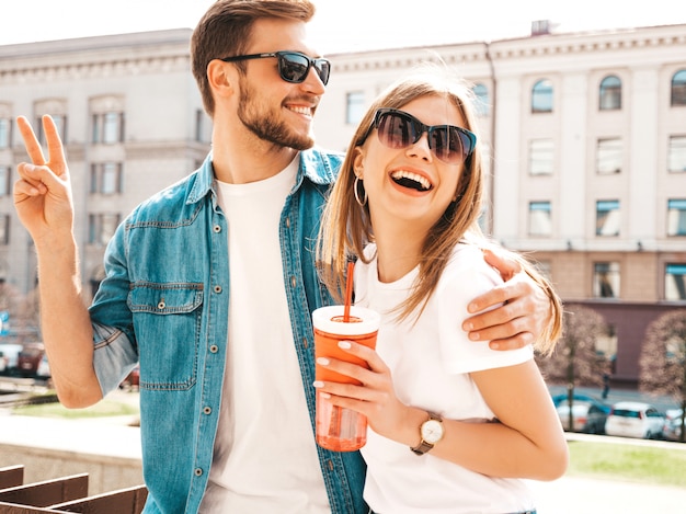 Retrato de niña hermosa sonriente y su novio guapo en ropa casual de verano. . Con botella de agua y paja