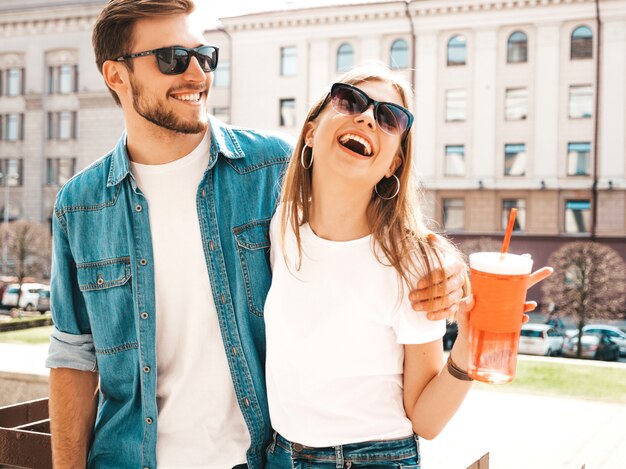 Retrato de niña hermosa sonriente y su novio guapo en ropa casual de verano. . Mujer con botella de agua y paja