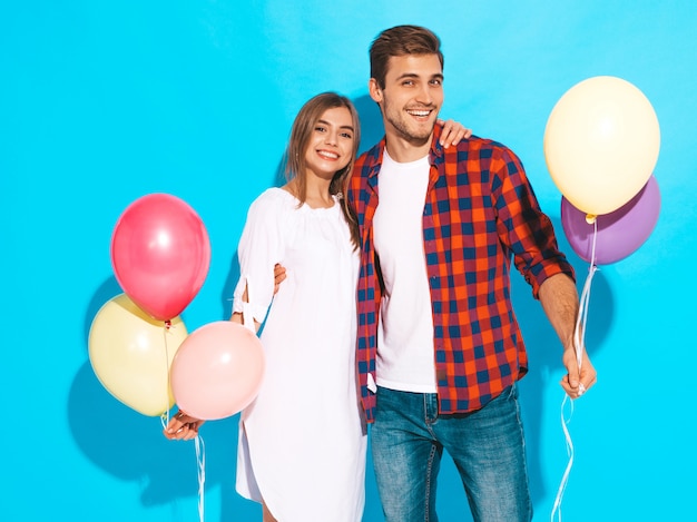 Foto gratuita retrato de niña hermosa sonriente y su novio guapo sosteniendo un montón de globos de colores y riendo. feliz cumpleaños