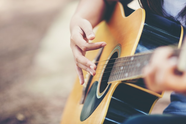 Retrato de niña hermosa tocando la guitarra con bicicleta en la naturaleza