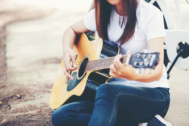 Retrato de niña hermosa tocando la guitarra con bicicleta en la naturaleza