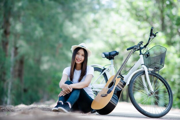 Retrato de niña hermosa tocando la guitarra con bicicleta en la naturaleza