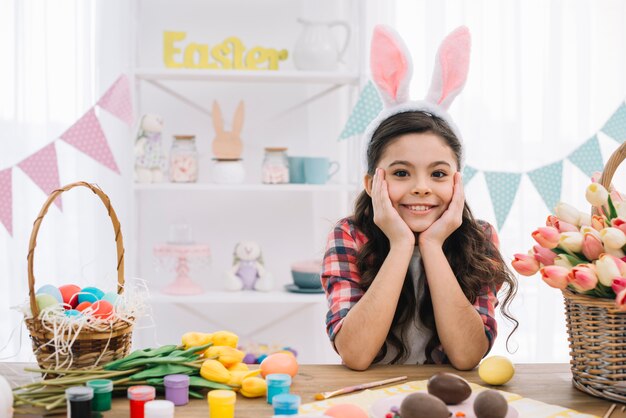 Retrato de una niña con huevos de pascua; Pintura y tulipanes flores en mesa.