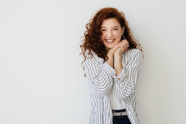 Retrato de niña de jengibre feliz con pecas sonriendo mirando a la cámara sobre fondo blanco.