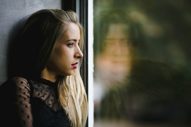 Un retrato de niña de lado cerca de una ventana