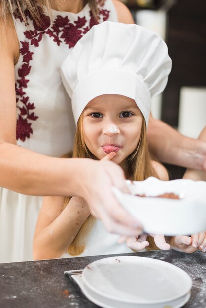 Retrato de niña lamiendo su dedo en la cocina