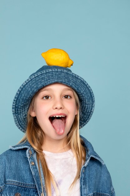 Retrato de niña con un limón en la cabeza y sacando la lengua