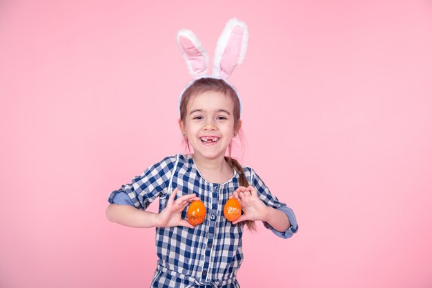 Retrato de una niña linda con los huevos de Pascua en un fondo rosado.