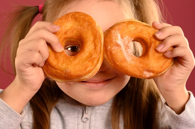 Retrato de niña linda jugando con donas