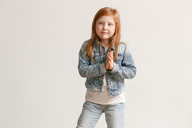 Retrato de niña linda niña en ropa elegante jeans mirando a cámara y sonriendo