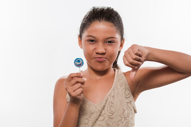 Retrato de una niña con lollipop gesticular pulgares abajo