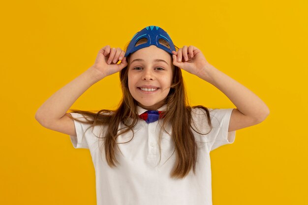 Retrato de niña con máscara de superhéroe sonriendo