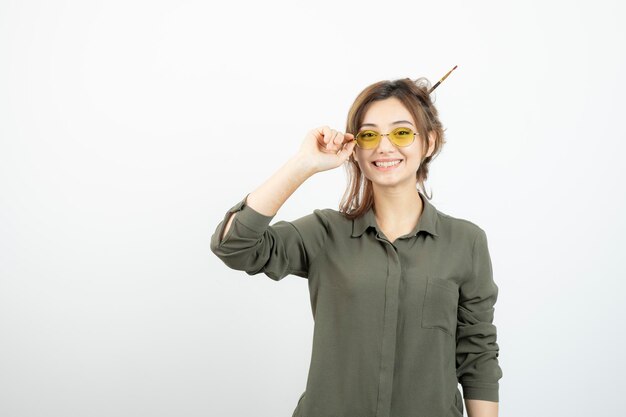 Retrato de niña con moño desordenado en gafas de pie y posando. foto de alta calidad