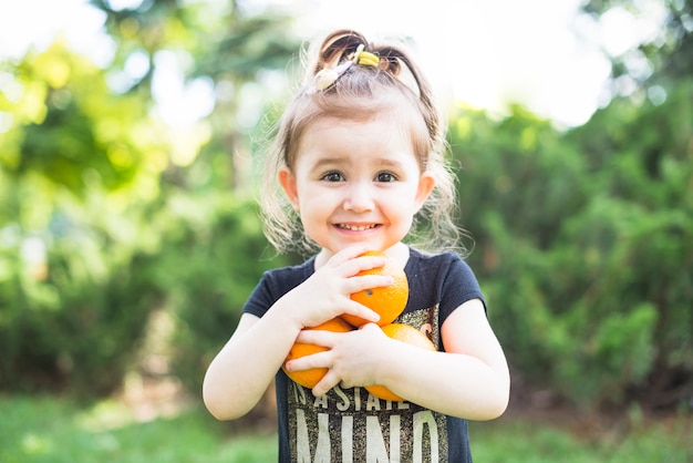 Retrato de una niña con naranjas maduras en las manos