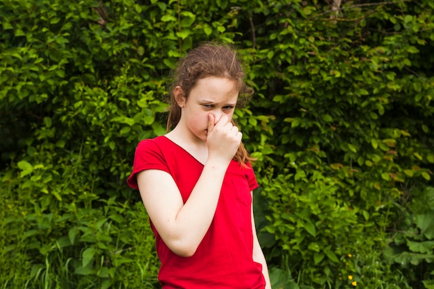 Retrato de niña con nariz en la naturaleza verde mirando a cámara