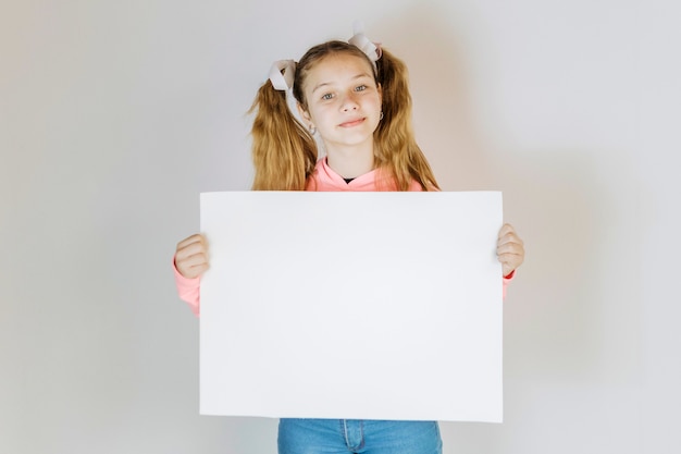 Foto gratuita retrato de una niña con papel cartón blanco en blanco