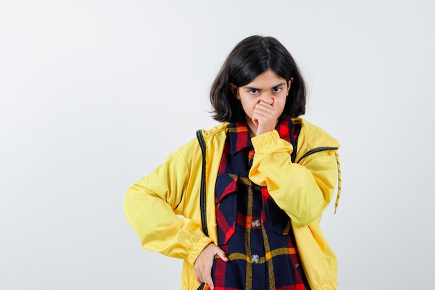 Foto gratuita retrato de niña pellizcando la nariz en camisa a cuadros, chaqueta y mirando linda vista frontal