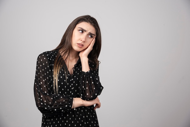 Retrato de niña pensativa mirando a otro lado y tomados de la mano en la cabeza.