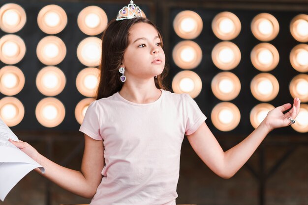 Retrato de una niña de pie ensayando frente a la luz de la etapa