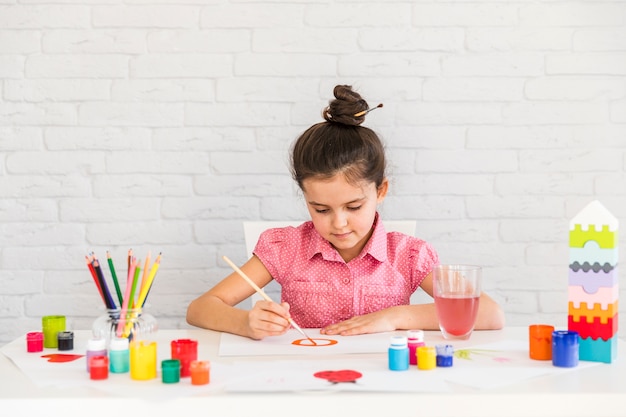 Retrato de una niña pintando sobre papel blanco con pincel