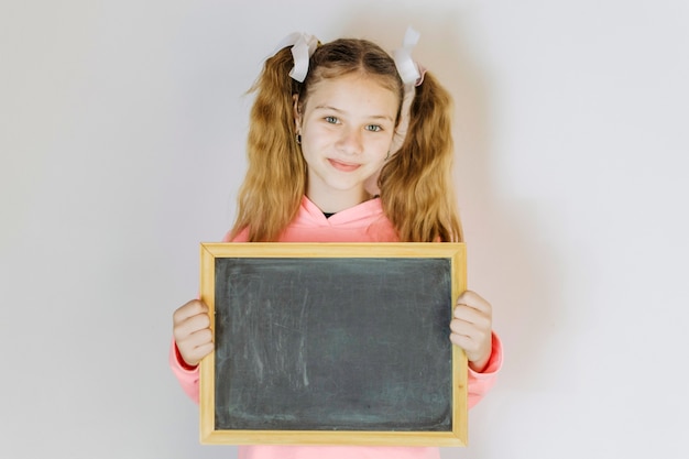 Foto gratuita retrato de una niña con pizarra en blanco