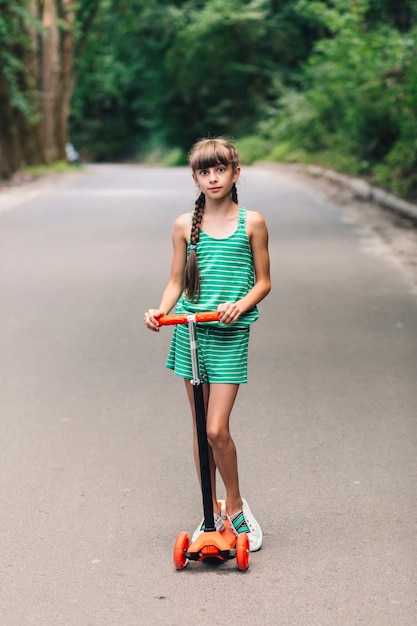 Foto gratuita retrato de una niña posando con patada scooter en la calle