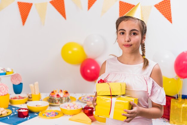 Retrato de una niña con regalos de cumpleaños en la mano.