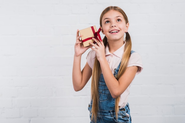 Retrato de una niña con regalos envueltos en la oreja contra el fondo blanco