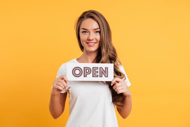 Retrato de una niña satisfecha sonriente con cartel de puerta abierta