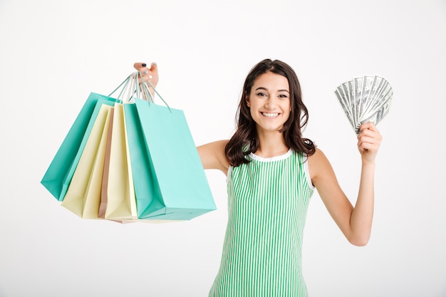 Retrato de una niña satisfecha en vestido con bolsas de compras