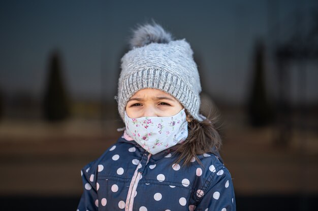 Retrato de una niña con sombrero y máscara durante la pandemia de coronavirus.