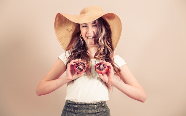 Retrato de una niña en un sombrero de verano con frutas sobre un fondo de color