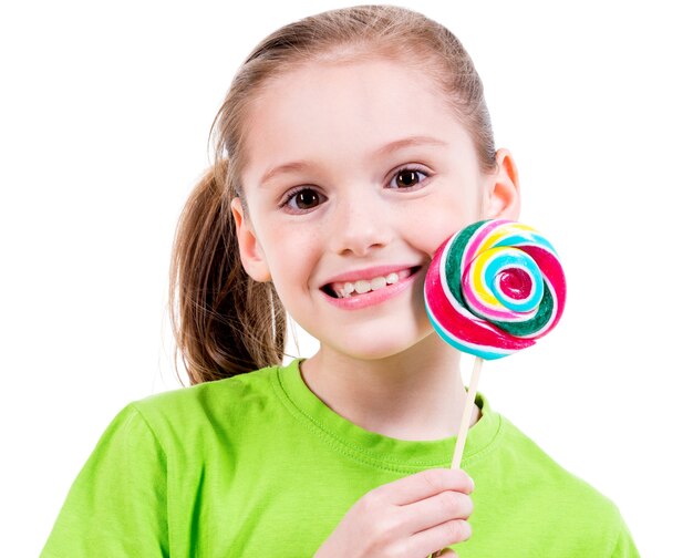 Retrato de niña sonriente en camiseta verde con caramelos de colores - aislado en blanco.