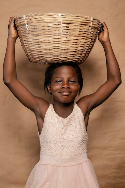 Retrato niña sonriente con cesta de paja en la cabeza.