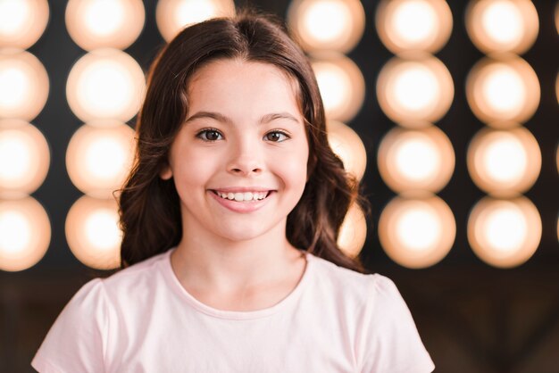 Retrato de niña sonriente contra la luz de la etapa que brilla intensamente