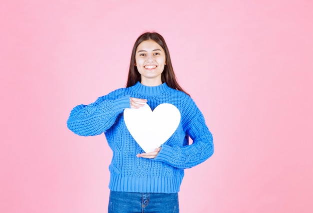 Foto gratuita retrato de niña sonriente con corazón blanco aislado en rosa.